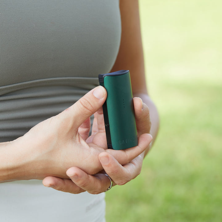 Green Miqro-C vaporizer in womans hand outside.